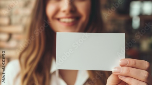 a beautiful woman holds a blank business card way out in front of her, focus on foreground