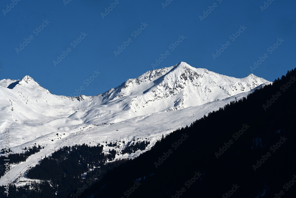 Skiwinter. Schneebedeckte Berge mit Wald und Skipisten bei Sonnenschein