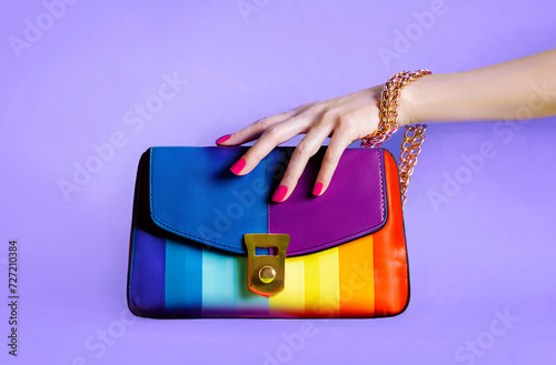 Colourful fashion rainbow purse with beautiful hand. isolated on purple background. 