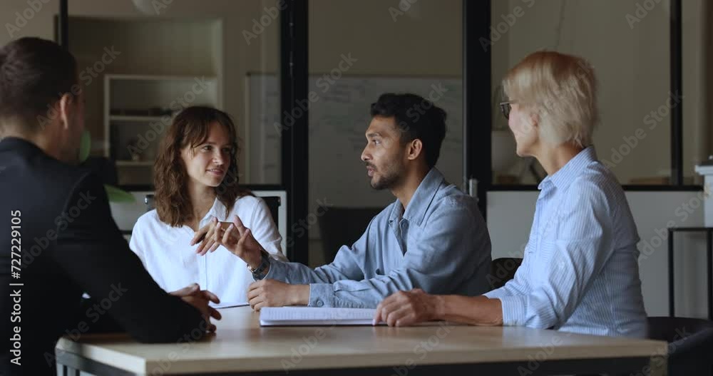 Young Indian project manager man in casual speaking to colleagues, startup partners at meeting table, explaining creative idea for brainstorming, work plan, cooperation strategy