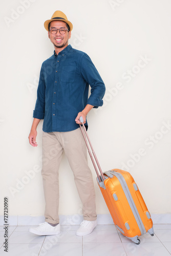 Full body portrait of a man walking with suitcase showing happy face expression photo