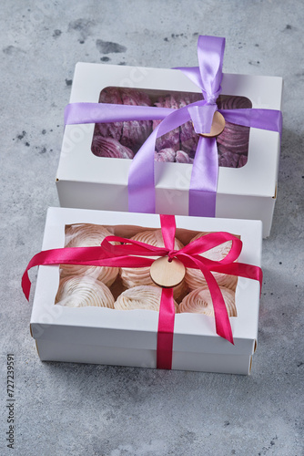 Zephyrs in a gift box. Fruit dessert on an old wooden table. Apple marshmallows with berry puree