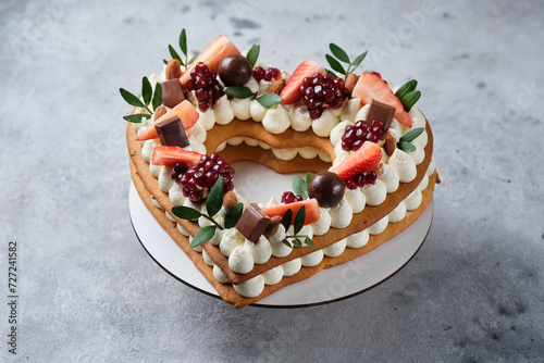 Honey cake decorated with fresh strawberries and herbs and cream cheese cream. Dessert for a loved one. Heart cake.