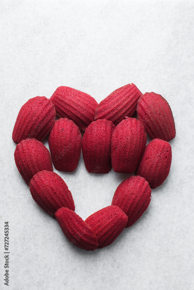 Fototapeta premium Red velvet madeleines on a marble tray shaped like a heart, red madeleines cake or cookies for valentines