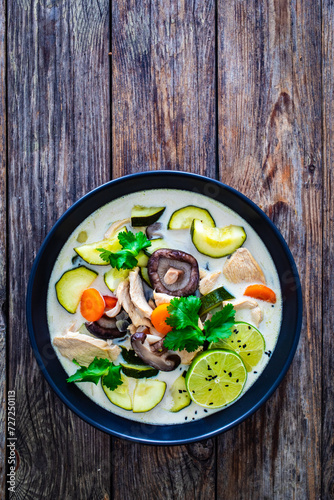 Tom Kha Gai soup - Thai soup with chicken breast nuggets and noodles on wooden table