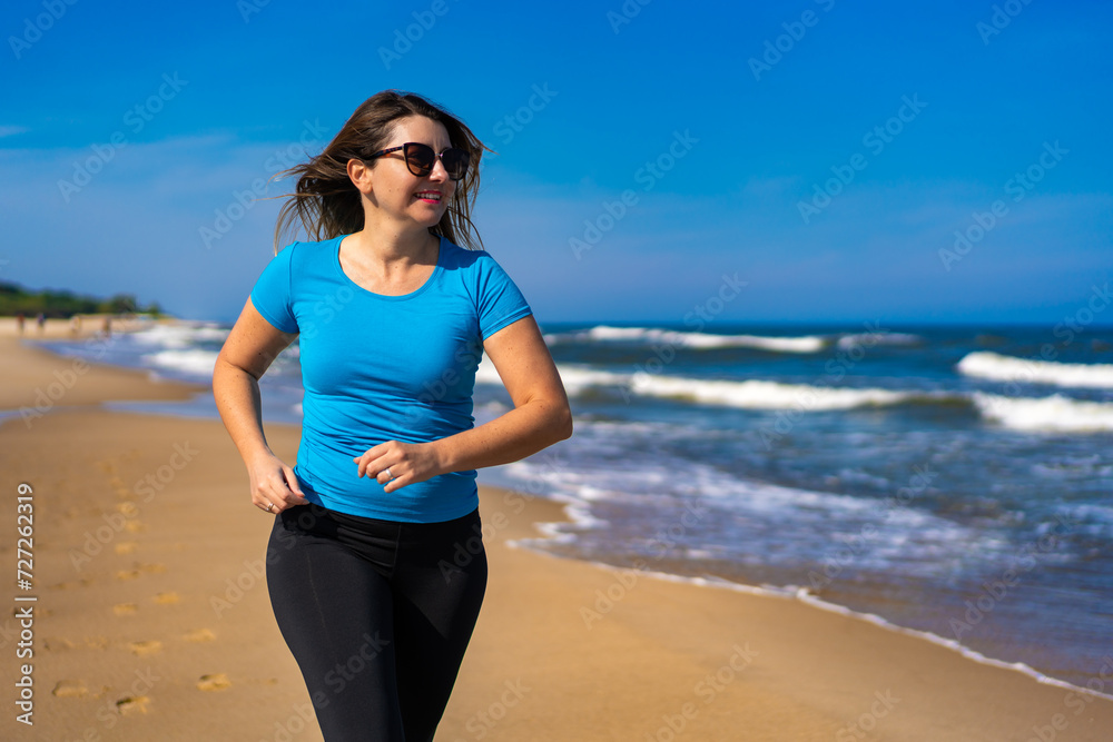 Mid adult beautiful woman running on sunny beach
Mid adult beautiful woman running on sunny beach