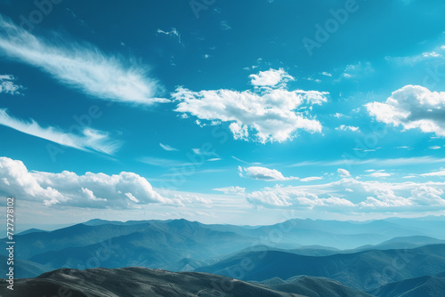 Expansive Mountain View Under Blue Skies An endless view of rolling mountain ranges under a vast blue sky scattered with wispy clouds, evoking a sense of peace and open space.  © nialyz