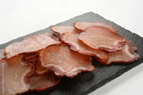 Embutido de lomo de cerdo cortado en rodajas en un plato de piedra negra