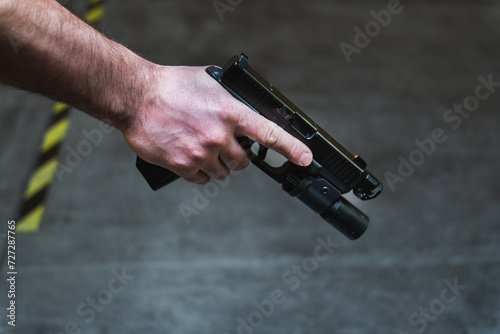 Tactical pistol with a flashlight in a man's hand, close-up photo.