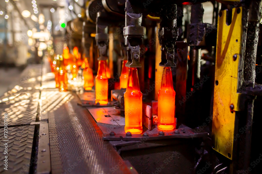 Glass factory, production of glass containers. Molten glass is blown into molds. Robotics in industry. Modern technologies, robotic machines produce products. Technological work at the plant.