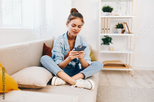 Smiling woman holding mobile phone, relaxing on cozy sofa in living room