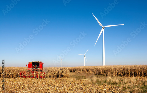 Eco friendly and clean energy producing wind turbines located on farm where corn is being harvested