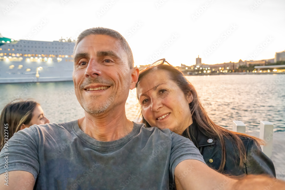 A family taking pictures at sunset near a cruise ship