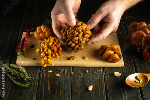 Close-up of a man hands sorting stacks of flammulina mushrooms on the kitchen table before cooking. photo