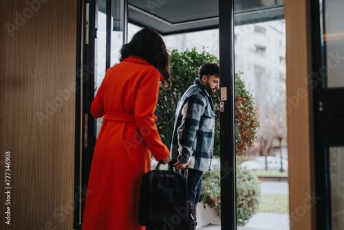 A man and woman in business attire are having a discussion as they exit an office building into the overcast weather, representing a corporate lifestyle.