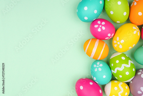 Colorful Easter Egg side border over a soft green paper background. Copy space.