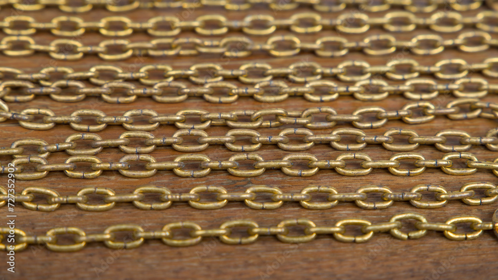 Close up of golden chain necklace on wooden background. Selective focus.