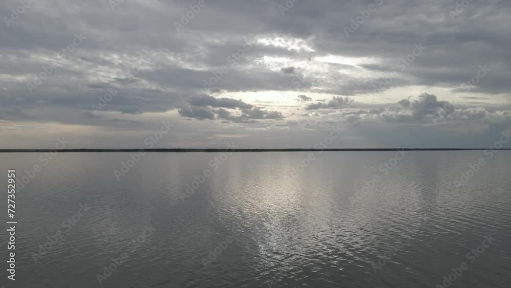 Drone moving slowly forward over a large lake that has small waves. The sky is full of gray clouds with bright patches. The sky colors are reflecting in the water.
Drone moving slowly forward over a large lake that has small waves. The sky is full of gray clouds with bright patches. The sky colors are reflecting in the water.