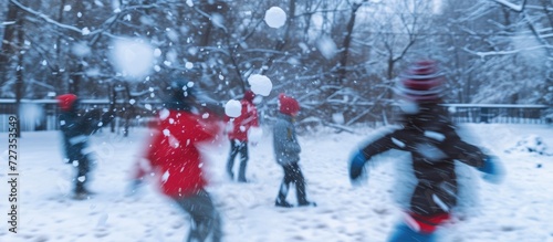 Blurred motion as young friends throw snowballs.