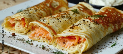 Salmon lavash rolls - a delicious combination of pancakes or crepes with fish and cheese served on a white plate.