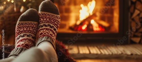 Closeup of a woman resting by the fireplace, wearing cozy socks. © Lasvu
