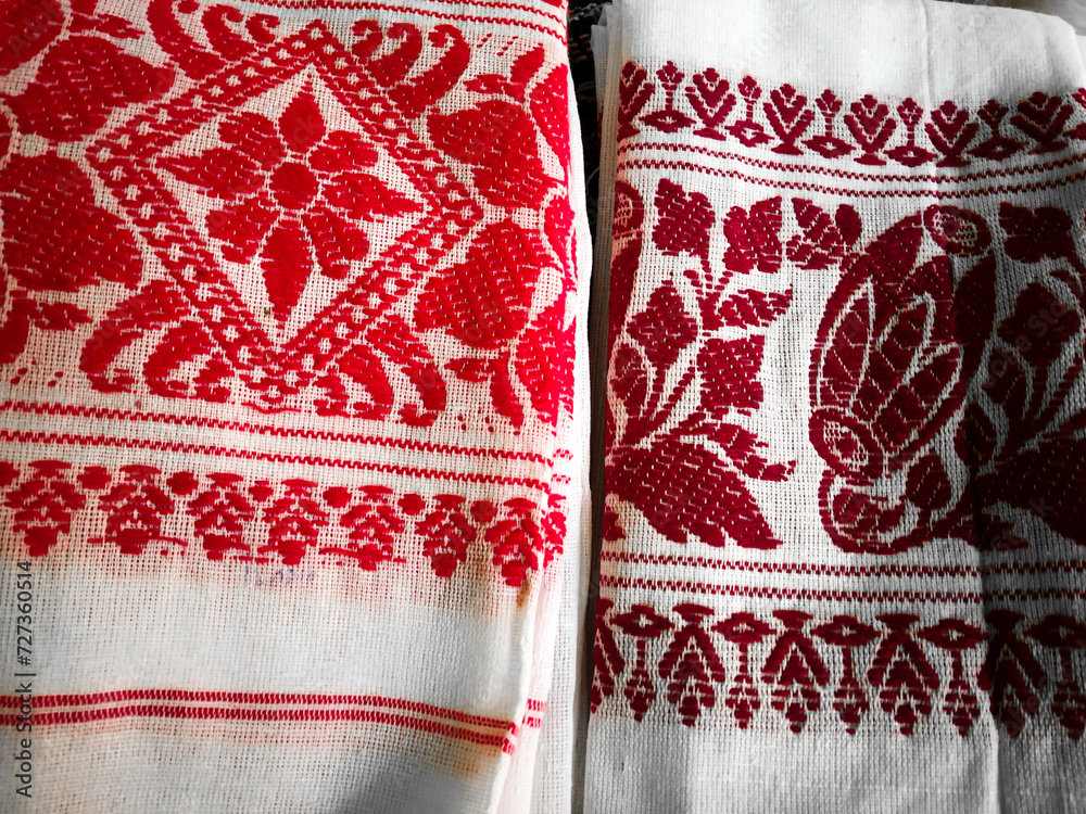 Gamosa or gamusa is a traditional textile pattern from Assam. It is a white piece of cloth with red stripes and red motifs, which is used in Bihu and resembles Ukrainian and Russian patterns. - obrazy, fototapety, plakaty 