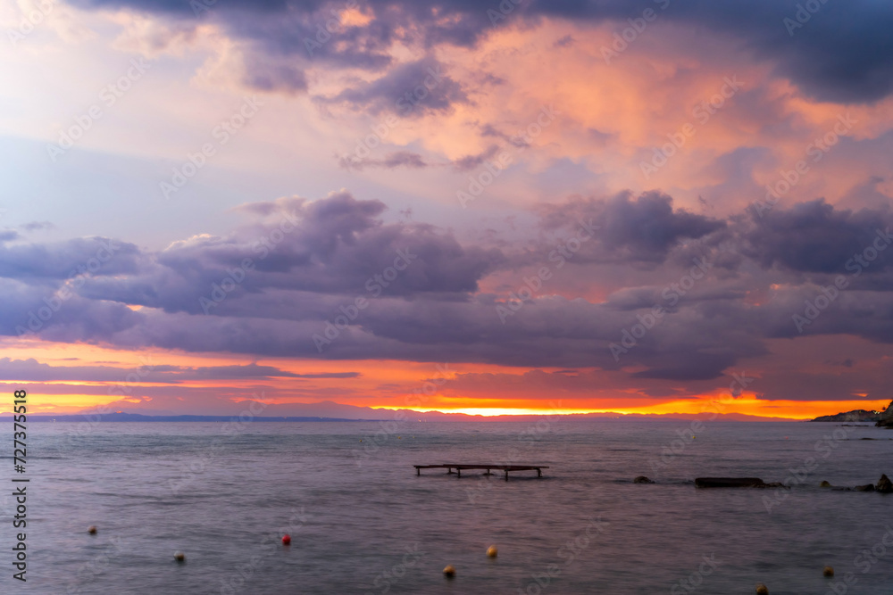 Long exposure shot of a sunrise or sunset on a sea waterbody against dramatic clouds located in Drosia, Zakinthos, Greece