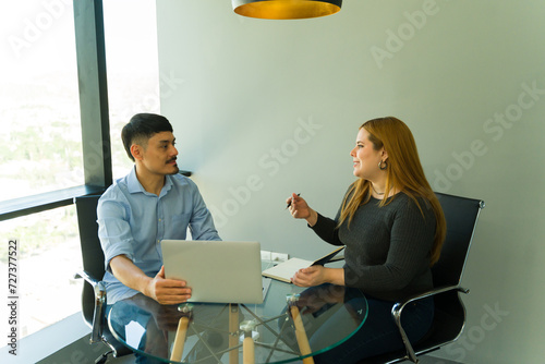 Two businesspeople dressed casually working together with a laptop computer and a notepad in an office