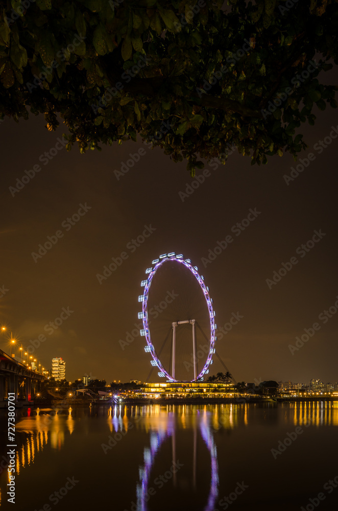 Obraz premium Singapore Ferris Wheel during night with reflection of its lights on water.