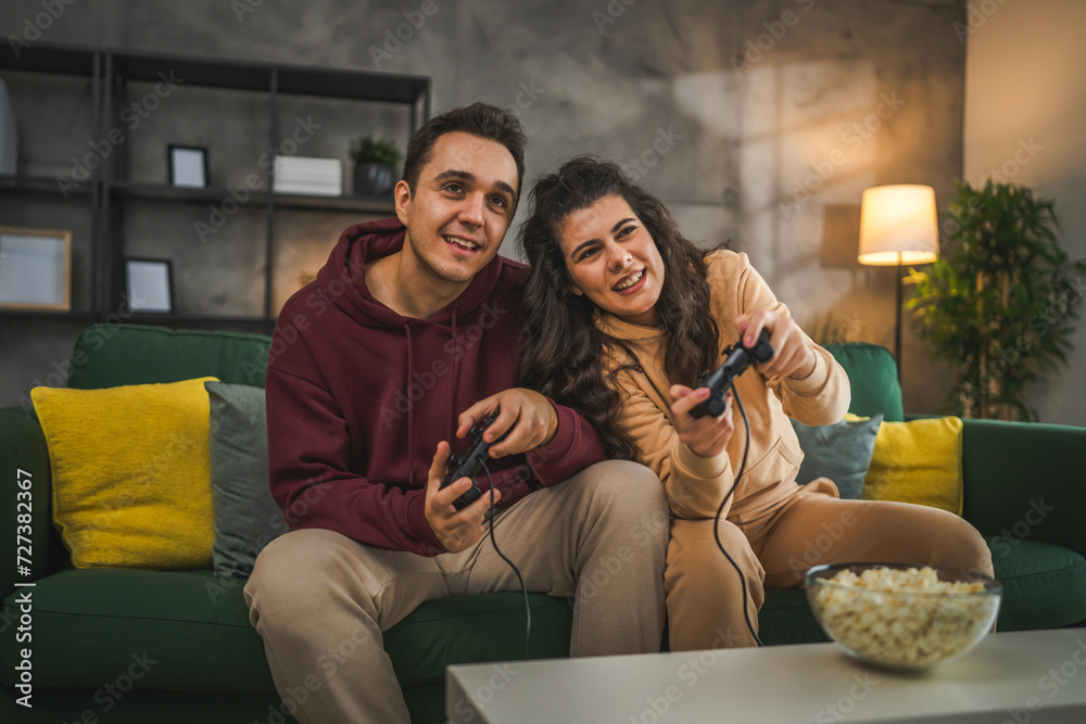couple man and woman husband wife play console video games at home