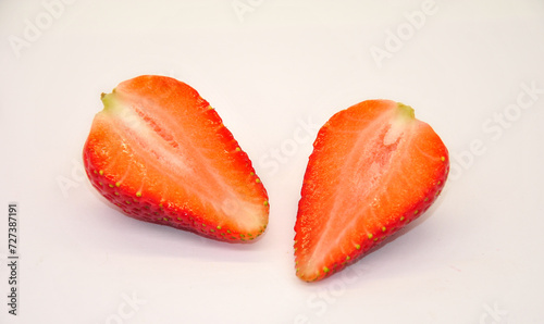 large ripe red strawberry cut in half on a light background