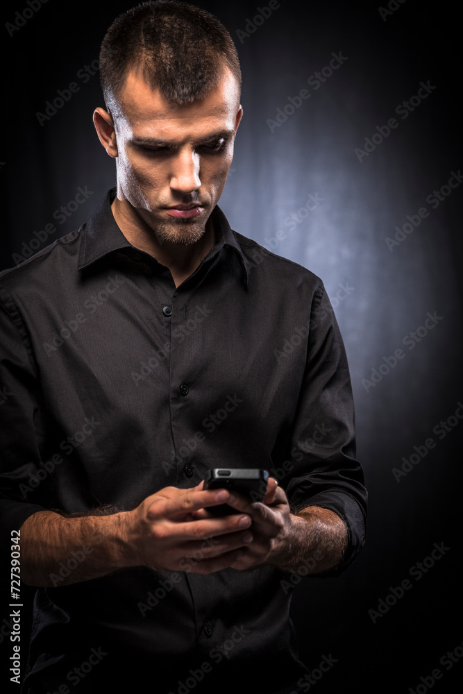 Young man in blacxk shirt using mobile phone Young man in blacxk shirt using mobile phone
