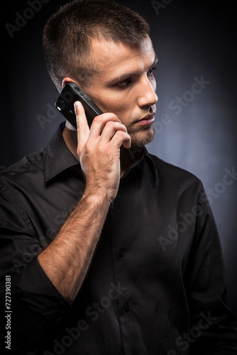 Young man in blacxk shirt talking on a mobile phone. photo