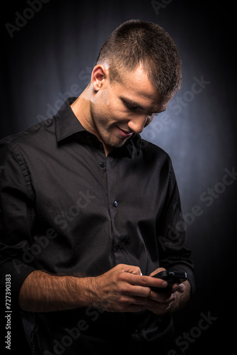 Young man in blacxk shirt using mobile phone photo