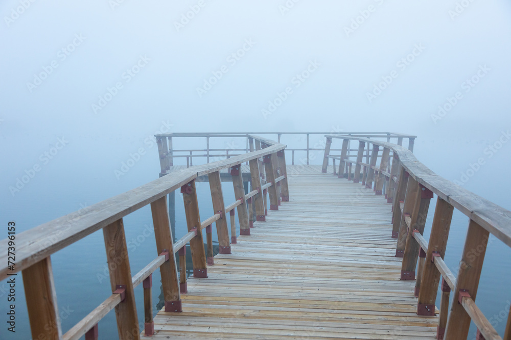 Wooden pier spanning a foggy lake Wooden pier spanning a foggy lake