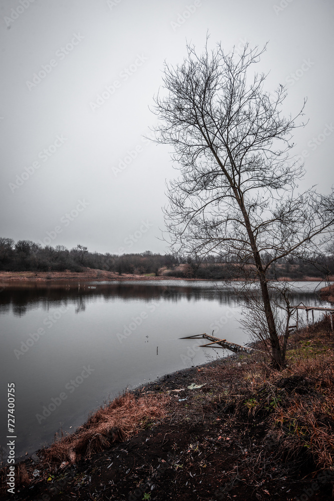 Fototapeta premium Mystery lake and forest in autumn colors . Lake in frost . Red colors . Fall on lake . House and buildings on the beach . Fishing house on the lake 