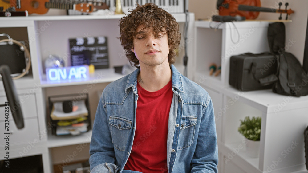 Young hispanic man with beard in studio with closed eyes wearing denim jacket and red shirt Young hispanic man with beard in studio with closed eyes wearing denim jacket and red shirt