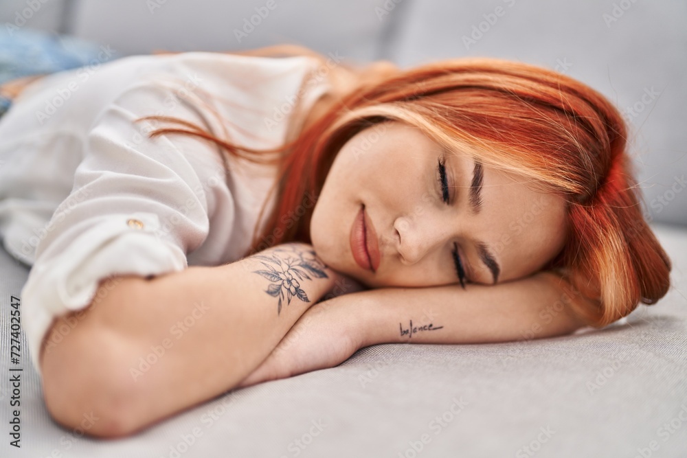 Young caucasian woman lying on sofa sleeping at home