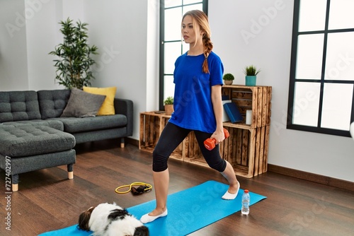 Young caucasian woman using dumbbells training at home