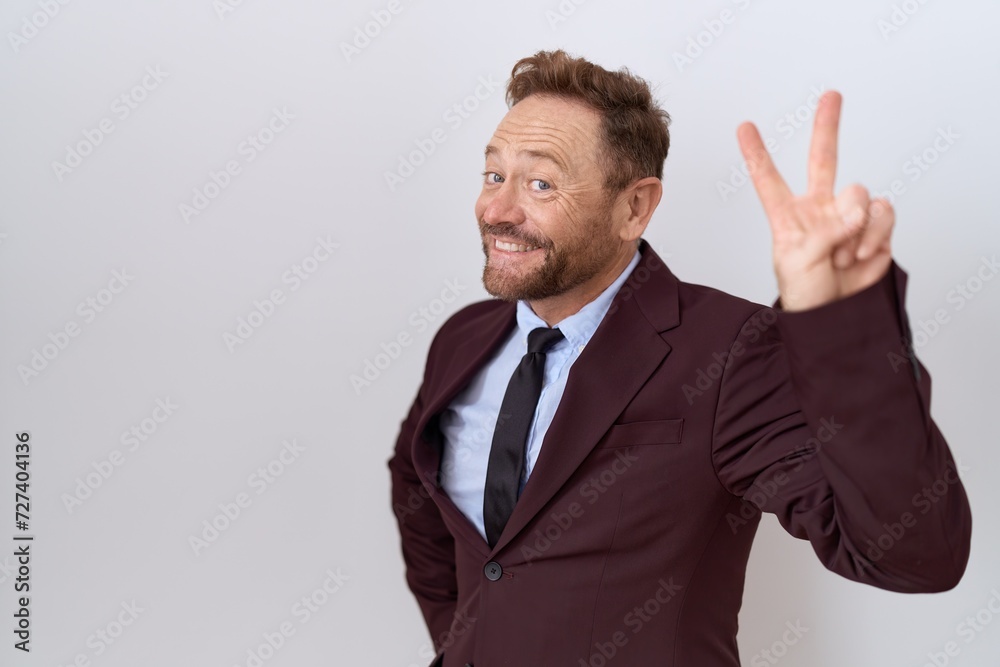 Middle age business man with beard wearing suit and tie smiling looking to the camera showing fingers doing victory sign. number two. Middle age business man with beard wearing suit and tie smiling looking to the camera showing fingers doing victory sign. number two.
