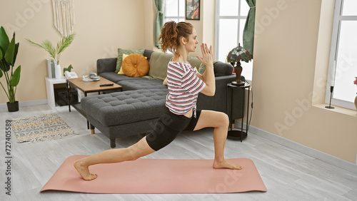 A young woman practices yoga in a modernly furnished living room, showcasing fitness and a relaxed lifestyle.