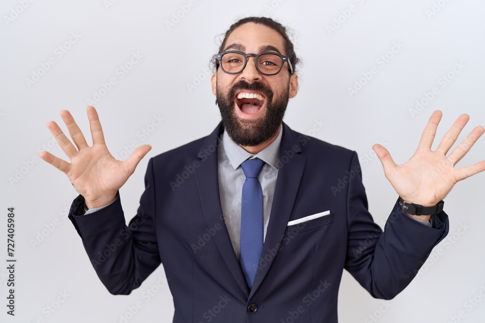 Hispanic man with beard wearing suit and tie celebrating crazy and amazed for success with arms raised and open eyes screaming excited. winner concept Hispanic man with beard wearing suit and tie celebrating crazy and amazed for success with arms raised and open eyes screaming excited. winner concept