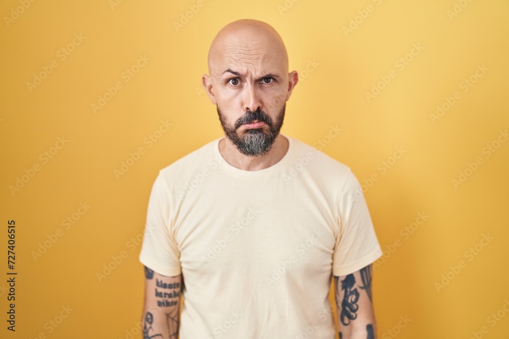 Hispanic man with tattoos standing over yellow background depressed and worry for distress, crying angry and afraid. sad expression. Hispanic man with tattoos standing over yellow background depressed and worry for distress, crying angry and afraid. sad expression.