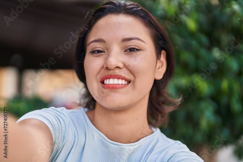 Young hispanic woman smiling confident making selfie by camera at street