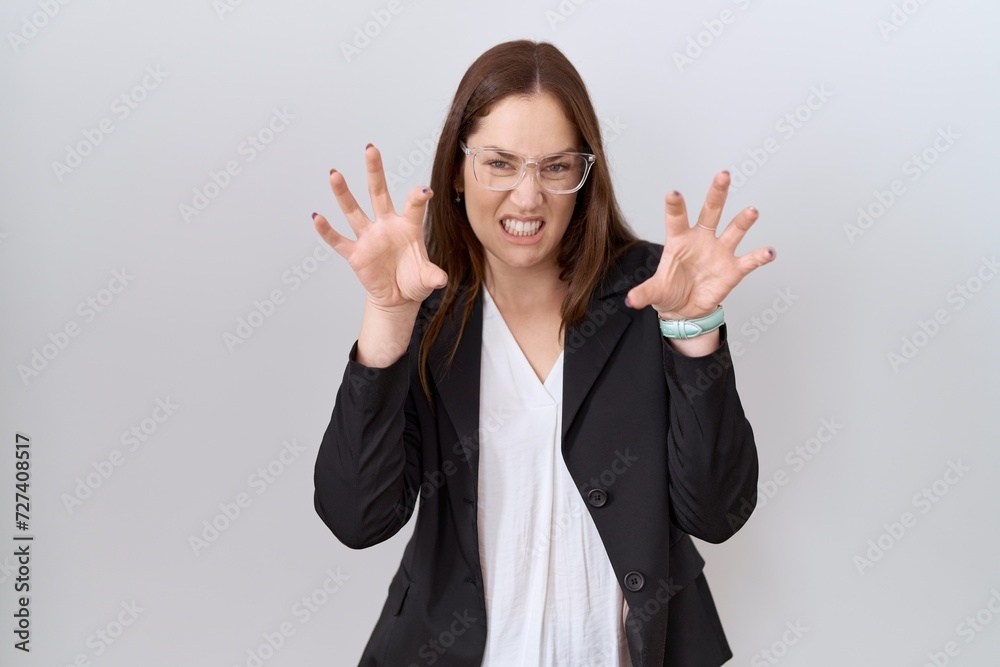 Beautiful brunette woman wearing business jacket and glasses smiling funny doing claw gesture as cat, aggressive and sexy expression
