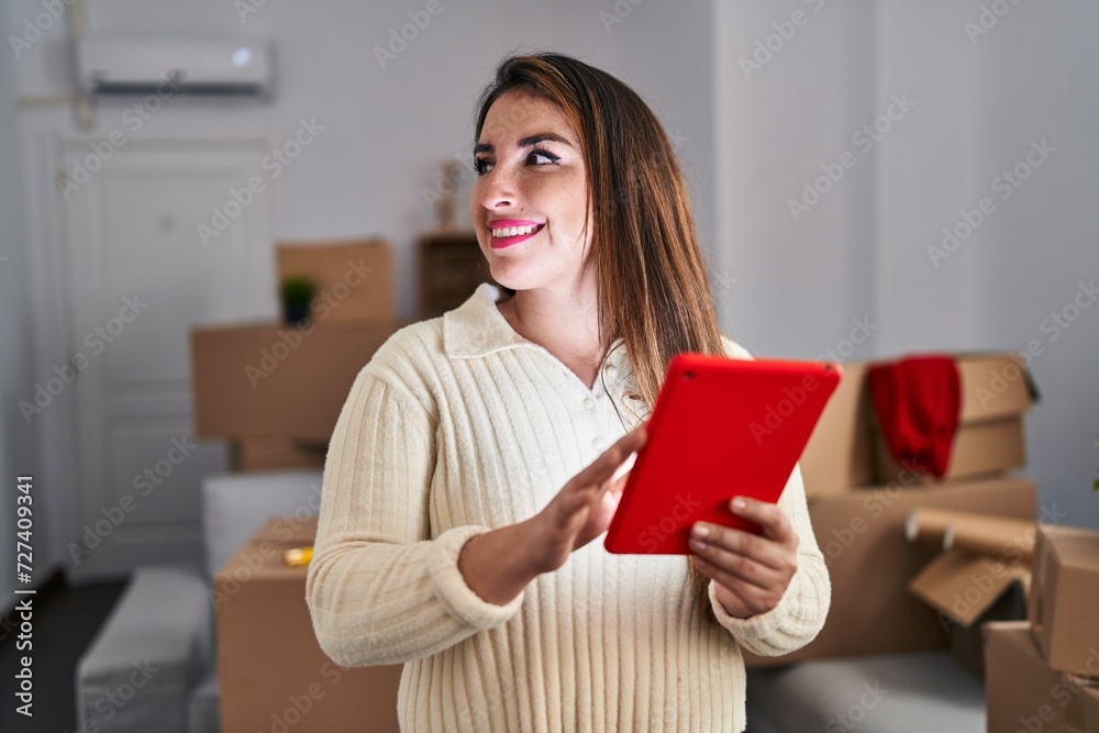 Young beautiful hispanic woman smiling confident using touchpad at new home Young beautiful hispanic woman smiling confident using touchpad at new home