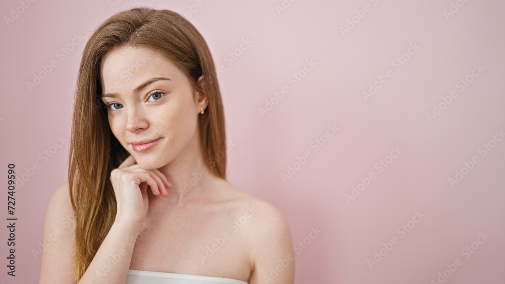 Young blonde woman smiling confident touching face with hand over isolated pink background Young blonde woman smiling confident touching face with hand over isolated pink background