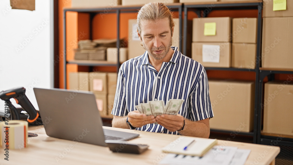 A mature businessman counts money at his warehouse workstation, looking focused and professional. A mature businessman counts money at his warehouse workstation, looking focused and professional.