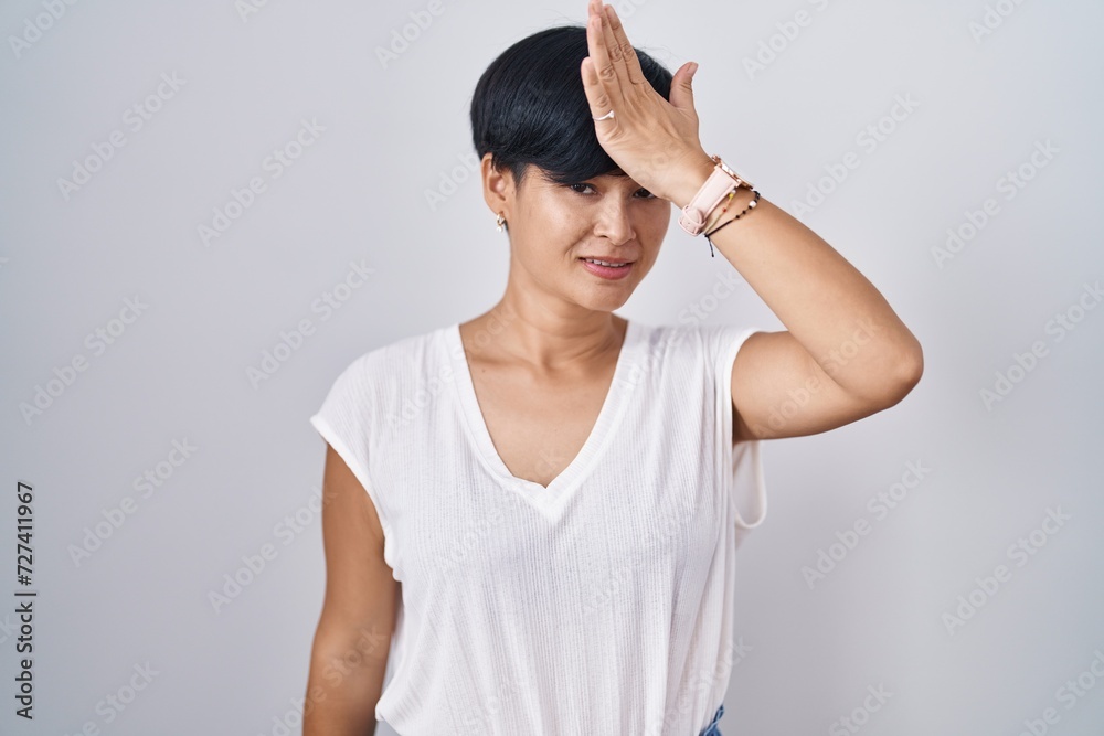 Young asian woman with short hair standing over isolated background surprised with hand on head for mistake, remember error. forgot, bad memory concept. Young asian woman with short hair standing over isolated background surprised with hand on head for mistake, remember error. forgot, bad memory concept.