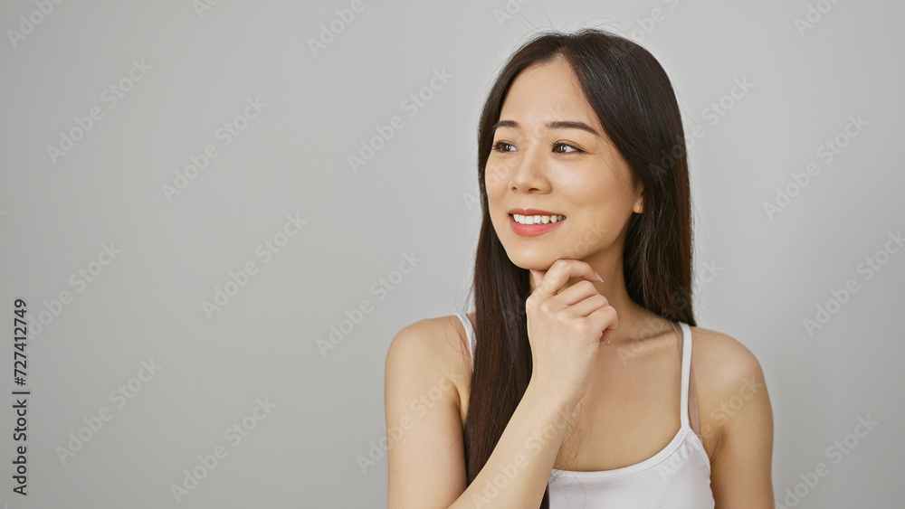 A thoughtful asian woman in a white tank top poses against an isolated white background, embodying casual elegance. A thoughtful asian woman in a white tank top poses against an isolated white background, embodying casual elegance.